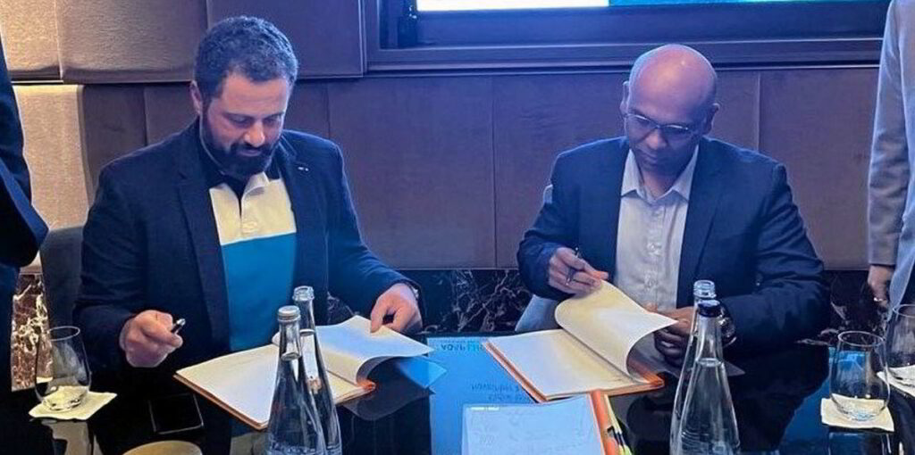 Two men sitting at a table signing papers.